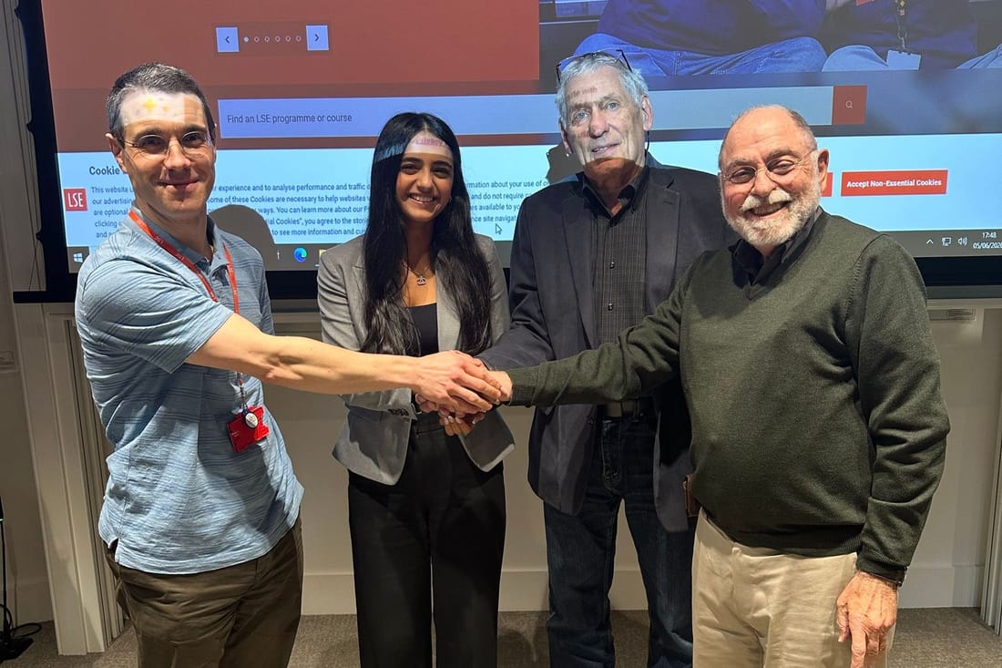 Elina shaking hands with Professor Douglas J. Besharov of the University of Maryland, Professor Neil Gilbert of UC Berkeley and another attendee, in front of the projected LSE homepage
