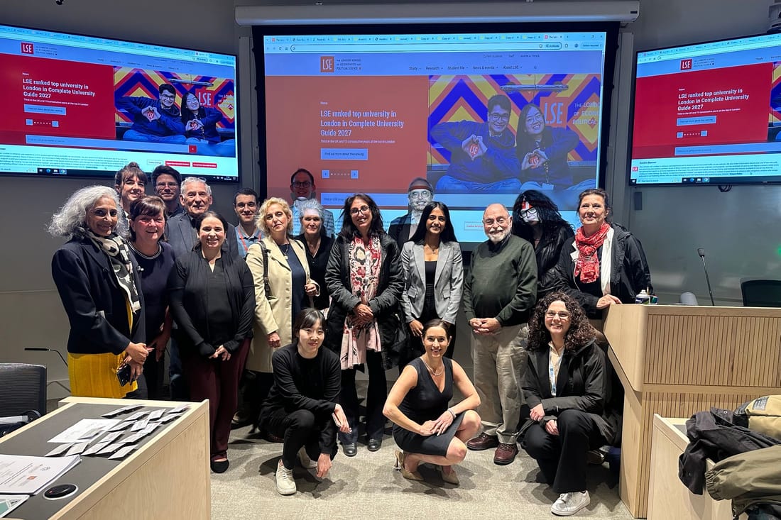 Elina with about twenty conference participants in an LSE seminar room, in front of screens showing the LSE homepage